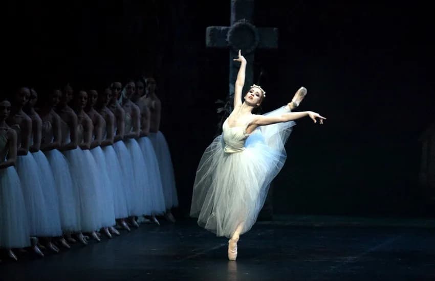 Une soliste en arabesque devant une longue file de danseuses en tutus blancs