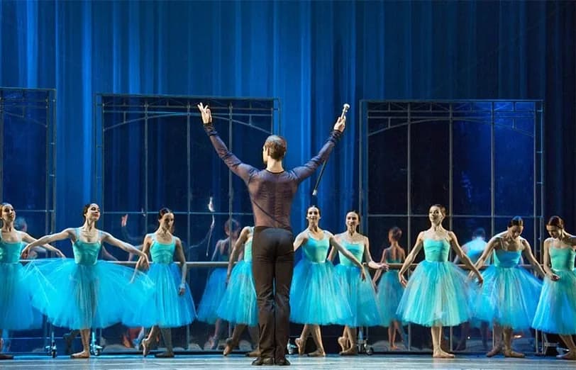 Danseur de dos, bras levés, face à une ligne symétrique de ballerines