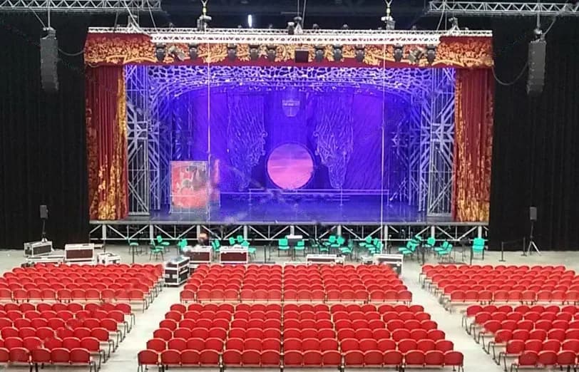 Décor de théâtre éclairé en bleu sous un cadre de scène rouge et or