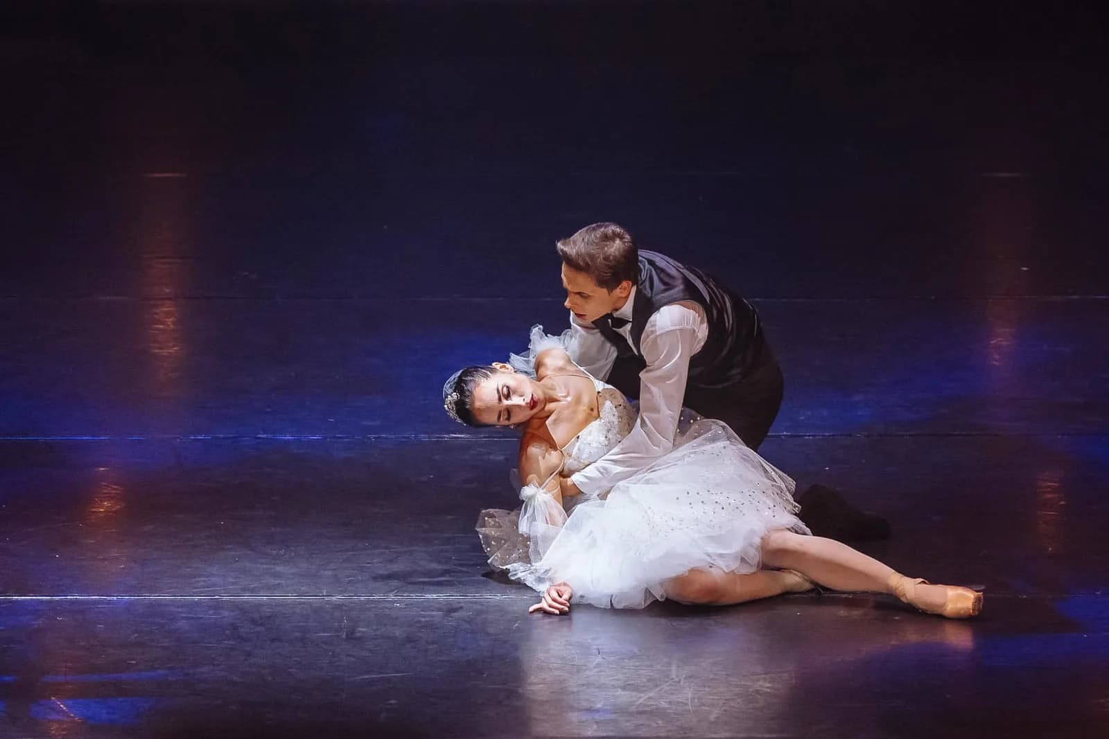 Duo au sol, un danseur penché sur une danseuse en tutu romantique