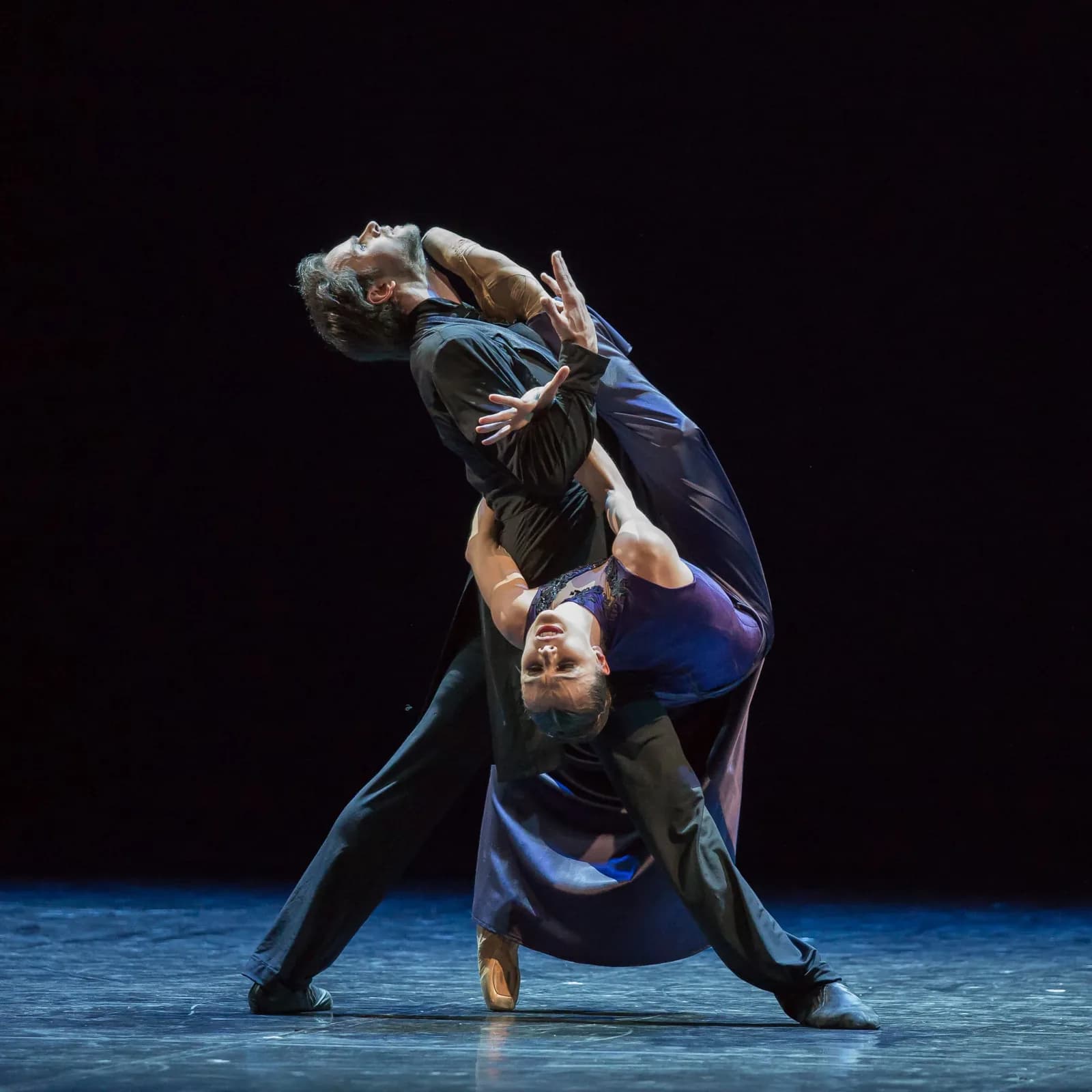 Couple enlacé : un homme en manteau long renverse une danseuse