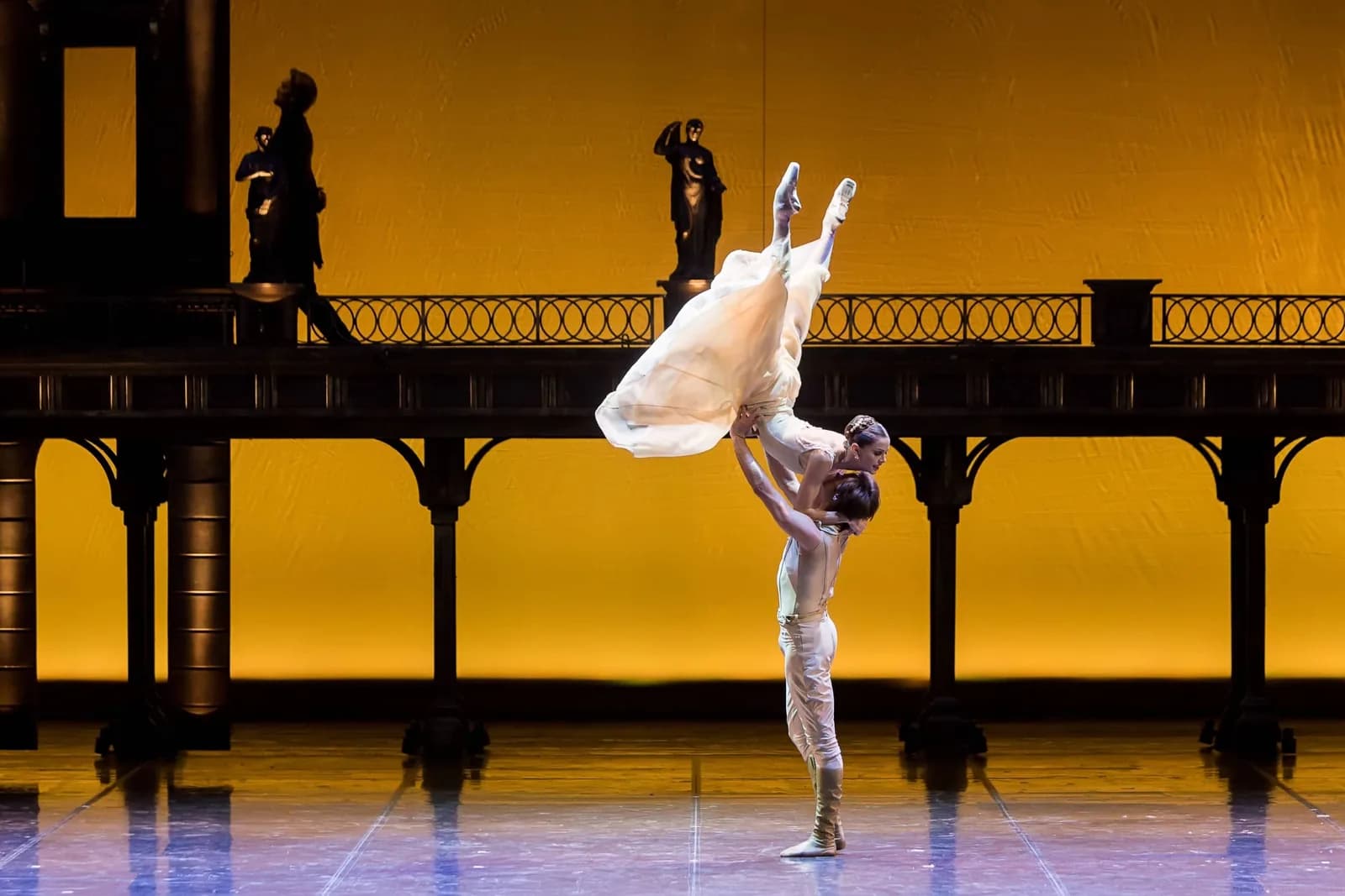 Danseuse en robe pâle portée en grand écart vertical