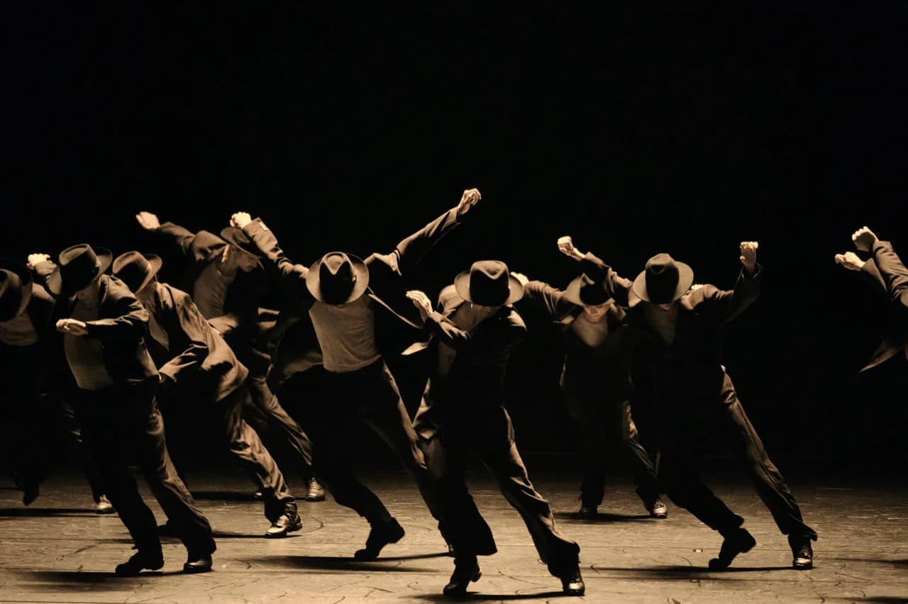 Danseurs en costume et chapeau, bras tendus, dans une lumière sépia