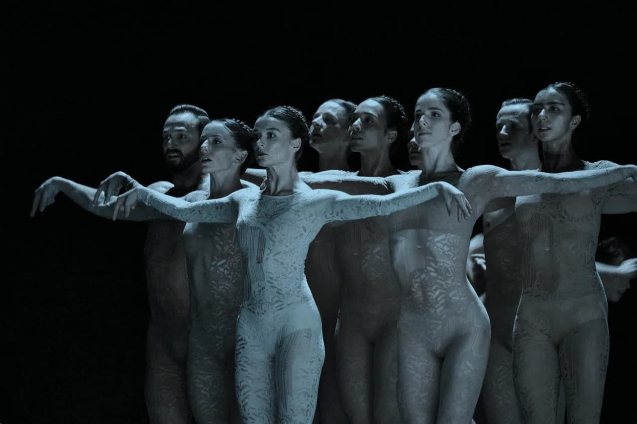 Rangée de danseurs en combinaisons pâles alignés face au public