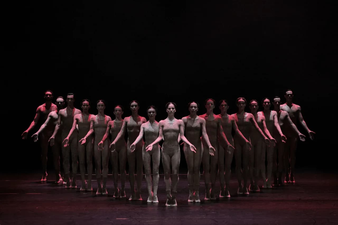 Rangée de danseurs éclairée de rouge, plateau plongé dans le noir
