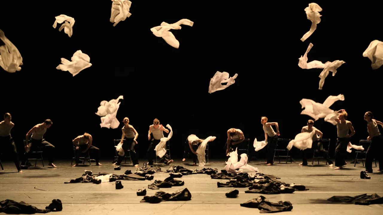 Les danseurs lancent des vêtements clairs qui flottent dans le noir