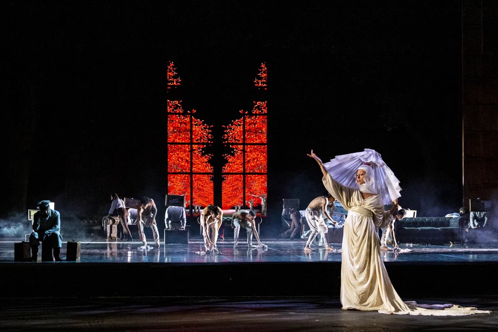 Deux hautes portes rougeoyantes dans la brume, une danseuse en robe claire