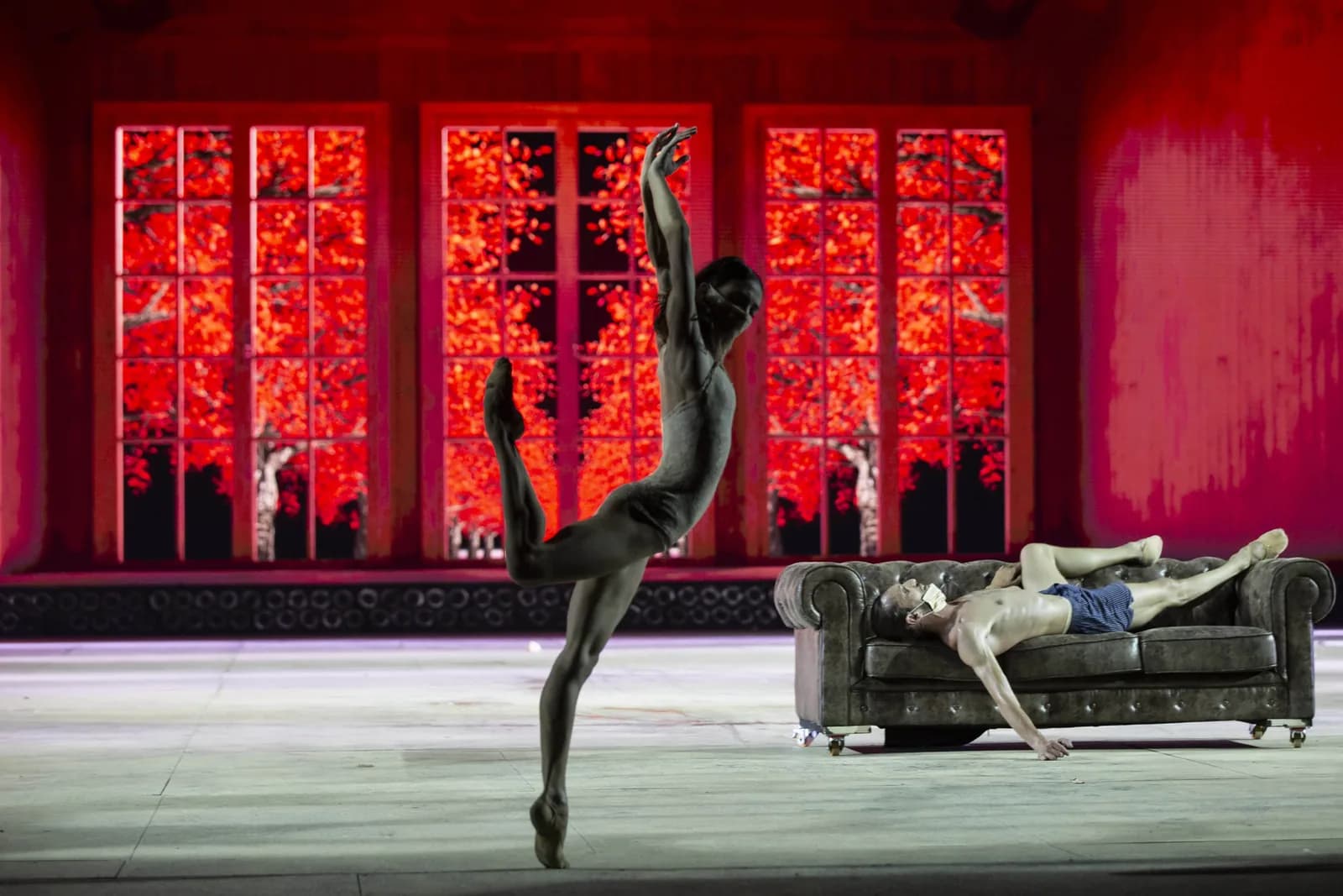 Danseur en arabesque haute devant des fenêtres rouges incandescentes