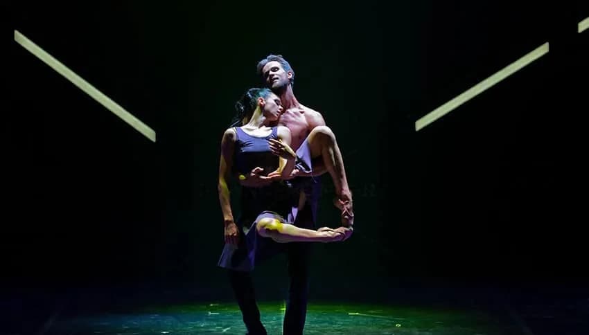 Couple porté sur un plateau vert sombre traversé de barres métalliques