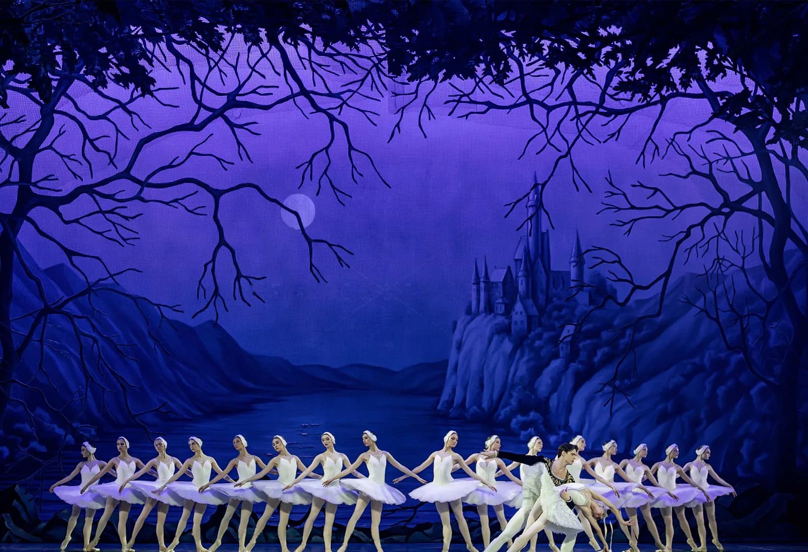 Deux longues lignes de danseuses traversent le plateau sous un ciel nocturne