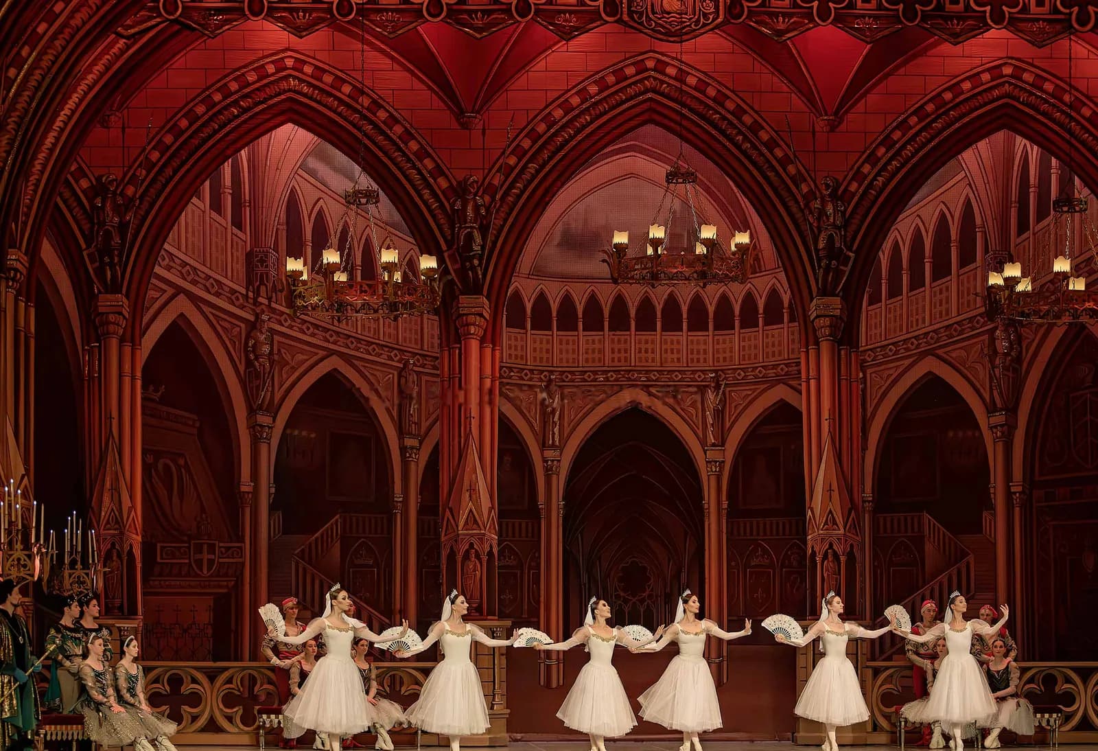 Vaste salle de bal aux tons rouges, les danseuses alignées au bas du plateau