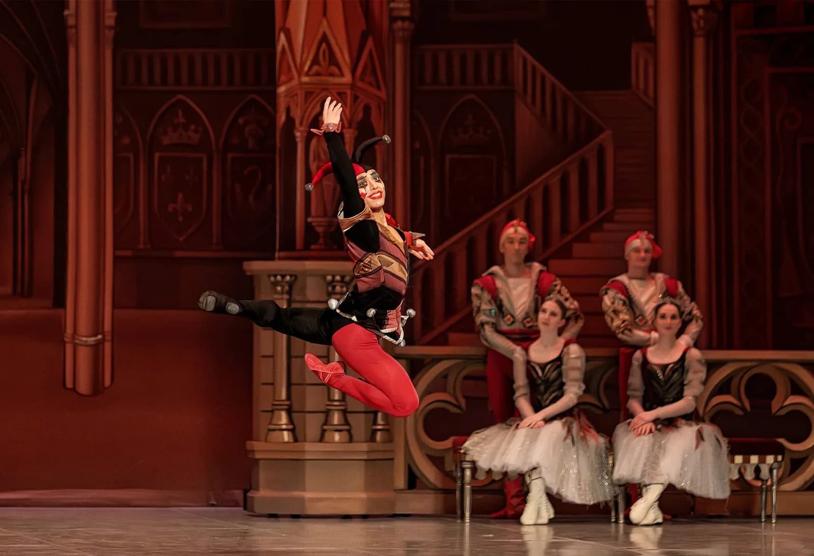 Le bouffon en costume rouge saisi en plein saut devant le grand escalier
