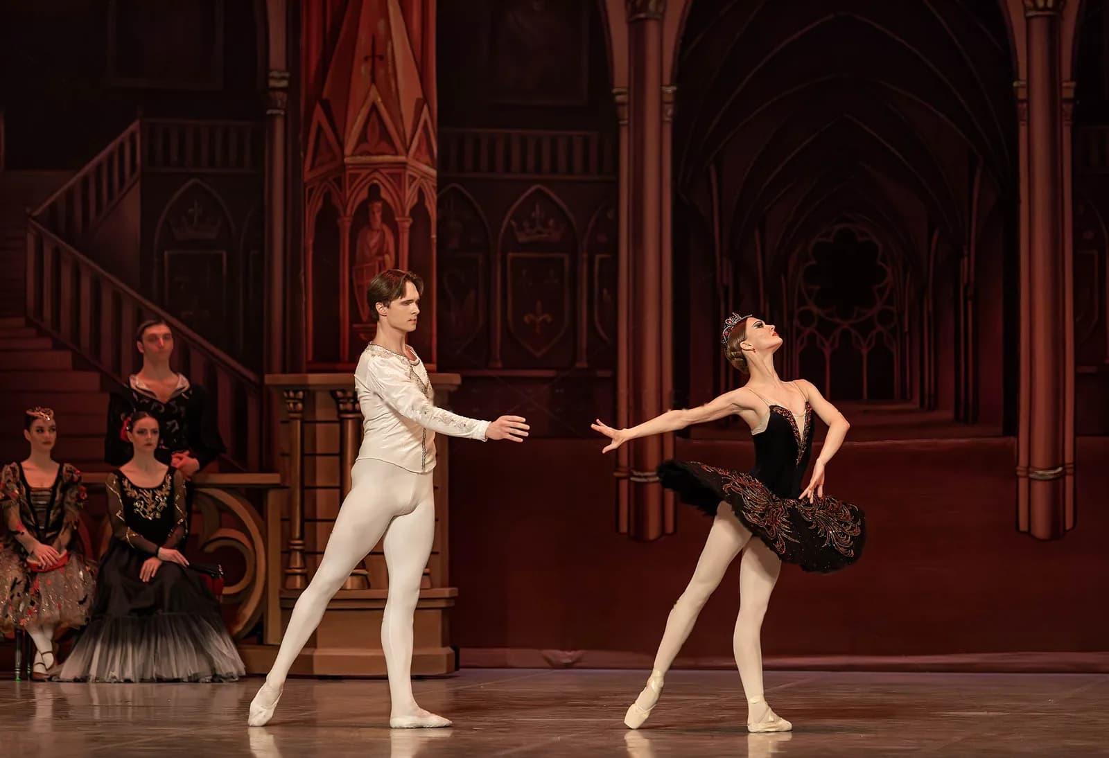Un danseur en pourpoint blanc tend la main vers une danseuse en tutu noir