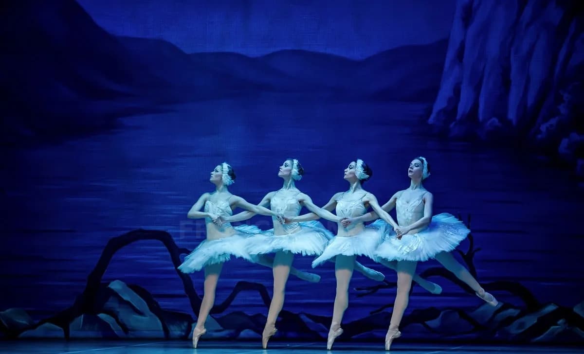 Quatre danseuses en tutu blanc, bras entrelacés, dans la lumière froide du lac