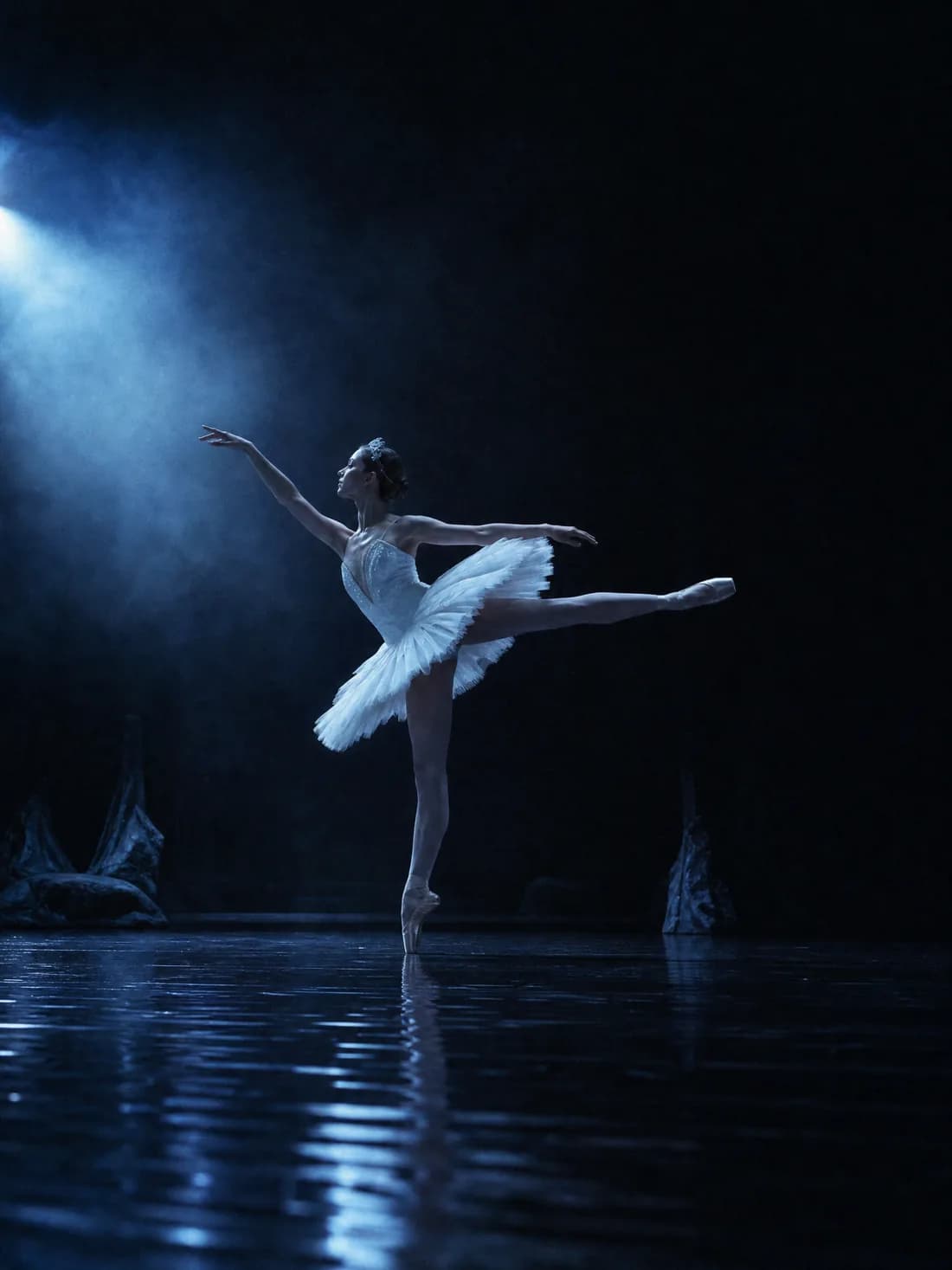 Une ballerine seule en tutu blanc en arabesque, sous une lumière lunaire bleue, reflet sur le plateau