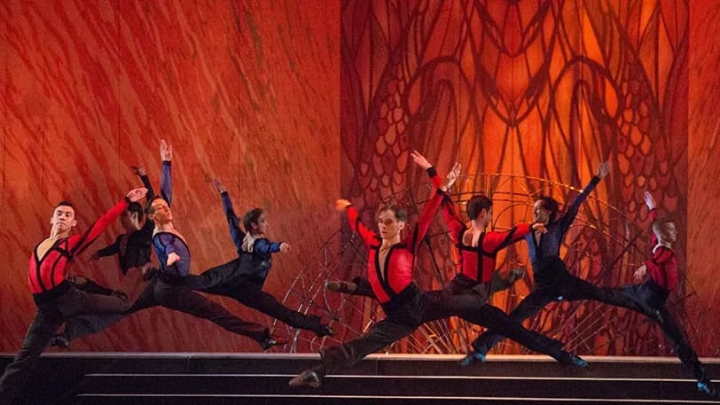 Deux danseurs en saut symétrique devant un fond orange incandescent