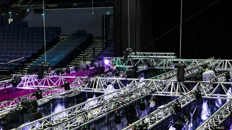 Salle obscure vue depuis les gradins, structures de scène soulignées de lumière
