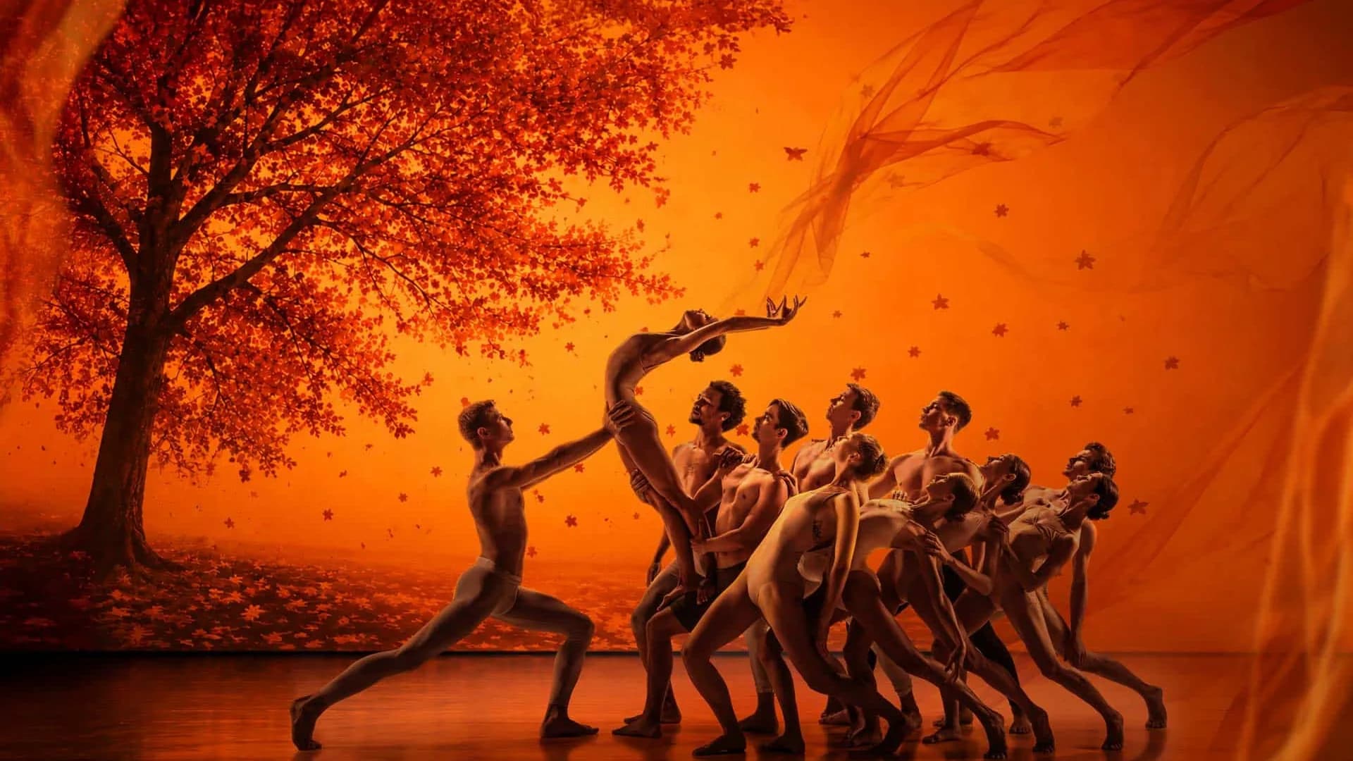 L'automne : un arbre rouge, les danseurs en diagonale dans une lumière orange incandescente