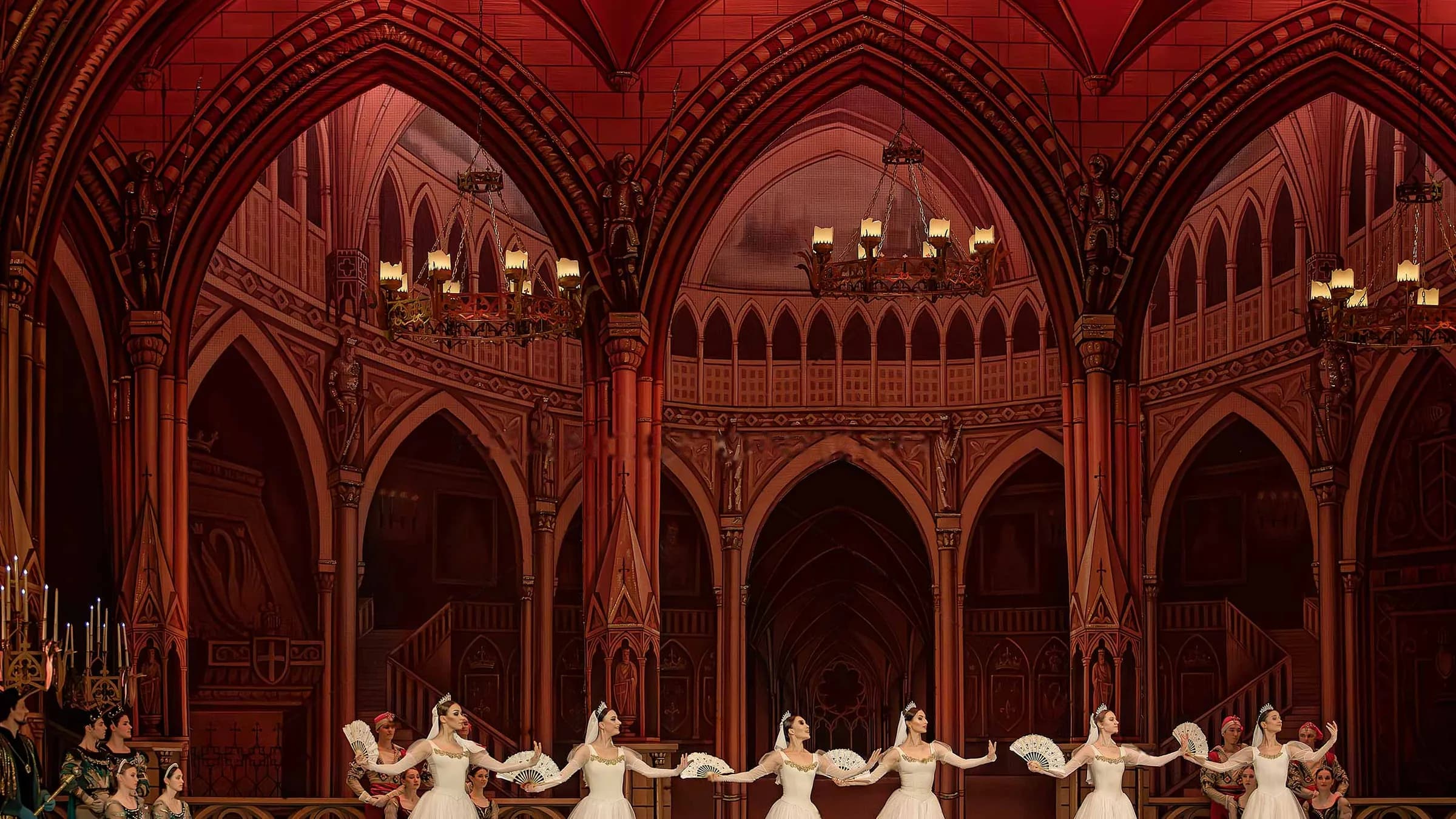 Vaste salle de bal aux tons rouges, les danseuses alignées au bas du plateau